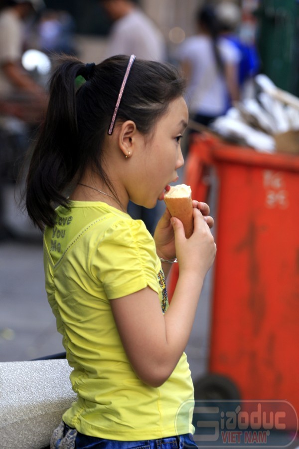 Một cháu bé thưởng thức kem Tràng Tiền ở một góc vỉa hè trên phố Tràng Tiền